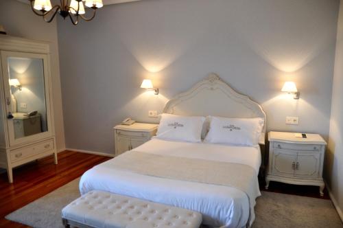 1 dormitorio con 1 cama blanca grande y espejo en Hotel Rural La Raposera, en Caravia