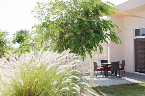 a patio with a table and chairs under a tree at Park Inn by Radisson Hotel and Residence Duqm in Duqm