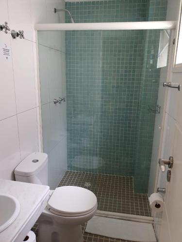 a bathroom with a toilet and a green tiled shower at SW Praia Hotel in Praia Grande