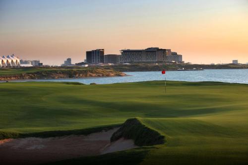 a golf course with a view of the ocean at Radisson Blu Hotel, Abu Dhabi Yas Island in Abu Dhabi