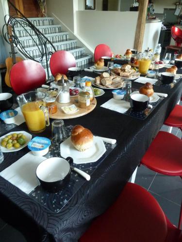 - une longue table remplie d'aliments pour le petit-déjeuner et de jus d'orange dans l'établissement B&B L'Atelier du Presbytère, à Saint-Maugan