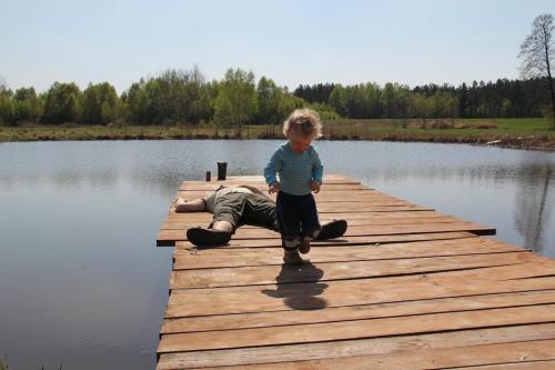 a young boy standing on a dock on a lake at Domek Drewniany in Nowa Wola