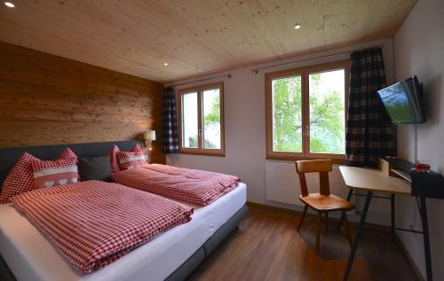 a bedroom with a bed and a desk and windows at Berggasthaus Eggberge in Altdorf