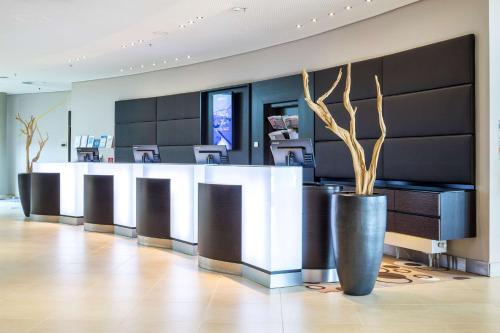 a lobby with a reception desk with trees in it at Radisson Blu Hotel, Hamburg Airport in Hamburg