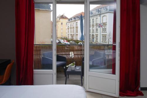 Cette chambre comprend un lit et une fenêtre avec des rideaux rouges. dans l'établissement BELCHAMPS Metz Gare Pompidou, à Metz