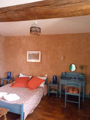 une chambre avec un lit avec des oreillers rouges et un bureau dans l'établissement B&B L'Atelier du Presbytère, à Saint-Maugan