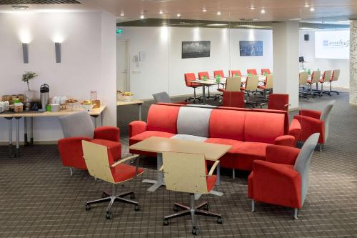 a waiting room with red chairs and desks and tables at Radisson Blu Hotel Olümpia in Tallinn