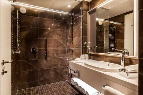 a bathroom with a tub, sink, mirror and bathtub at Radisson Blu Béke Hotel, Budapest in Budapest