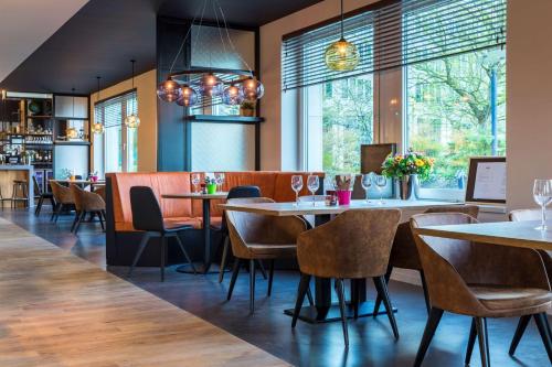 a restaurant with tables and chairs and windows at Park Inn By Radisson Brussels Airport in Diegem