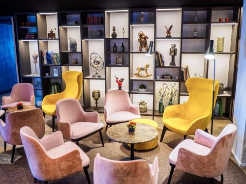 a room with yellow and pink chairs and tables at Radisson Blu Hotel, Bruges in Bruges