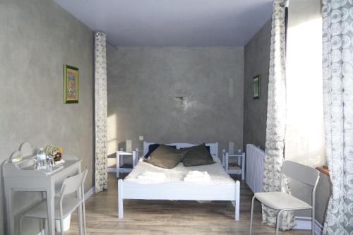 una camera da letto con un letto bianco e una scrivania di B&B L'Atelier du Presbytère a Saint-Maugan
