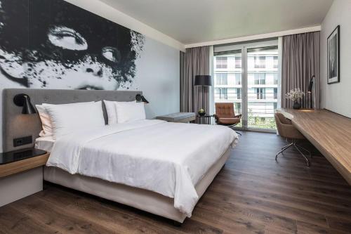 a bedroom with a large white bed and a large window at Radisson Blu Hotel Köln in Cologne