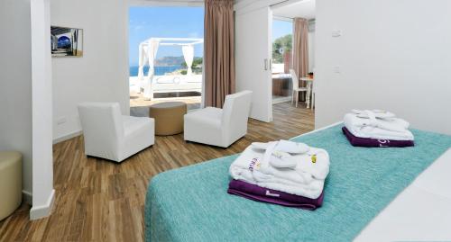 Pokój z 2 białymi krzesłami i ręcznikami na dywanie w obiekcie FERGUS Style Cala Blanca Suites w miejscowości Santa Ponsa