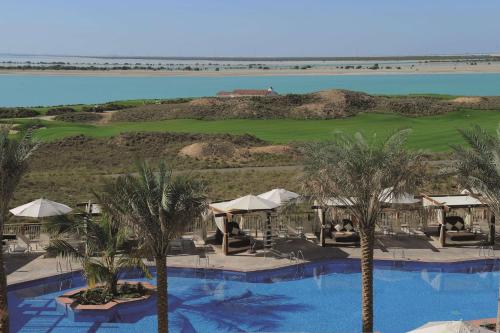 
a beach with palm trees and a pool of water at Radisson Blu Hotel, Abu Dhabi Yas Island in Abu Dhabi
