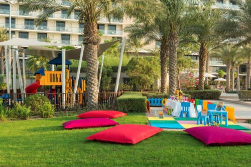 a park with tables and chairs and palm trees at Radisson Blu Hotel, Abu Dhabi Yas Island in Abu Dhabi