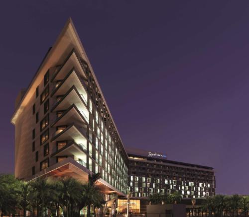 a lit up building with palm trees in front of it at Radisson Blu Hotel, Abu Dhabi Yas Island in Abu Dhabi