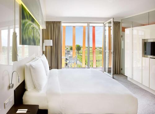ein Schlafzimmer mit einem großen weißen Bett und einem Balkon in der Unterkunft Radisson Blu Hotel & Convention Centre Kigali in Kigali