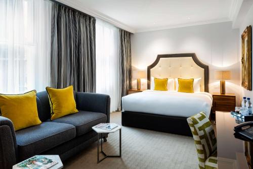 a hotel room with a bed and a couch at Radisson Blu Edwardian Vanderbilt Hotel, London in London