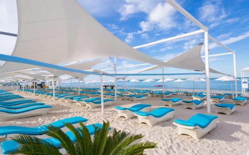 a beach with blue chairs and white umbrellas at Radisson Collection Paradise Resort and Spa Sochi in Adler