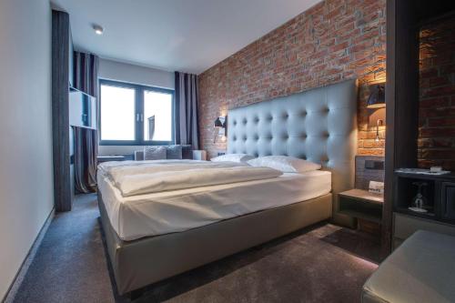 a bedroom with a large bed and a brick wall at Park Inn by Radisson Lübeck in Lübeck