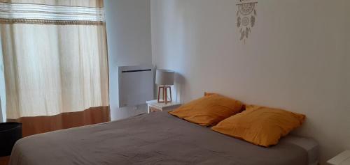 um quarto com uma cama com almofadas laranja e uma janela em Charmant T3 à proximité du Bassin em Arès