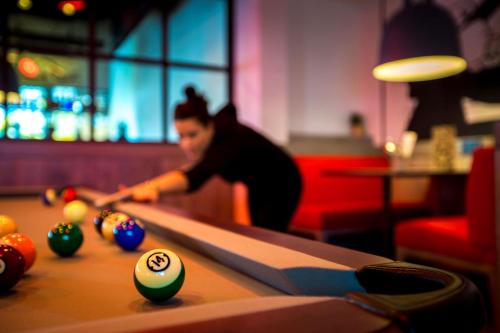 a woman playing a game of pool on a table at Radisson RED Brussels in Brussels
