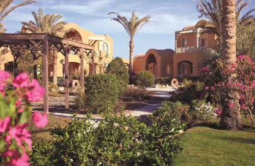 a house with palm trees and flowers in a yard at Radisson Blu Resort El Quseir in Quseir