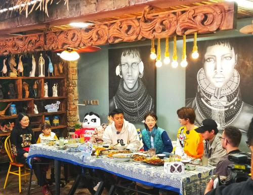 a group of people sitting at a table eating food at Hidden Garden Inn (Airport Transfer) in Jinghong