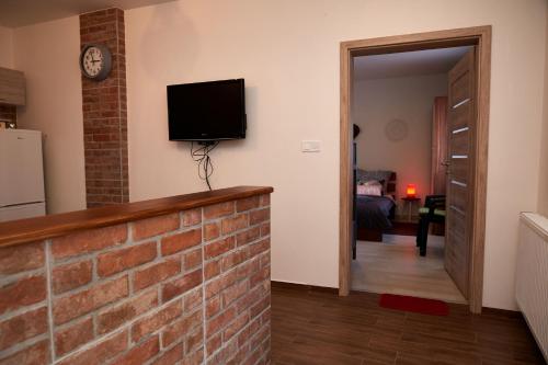 a living room with a brick wall and a tv on a wall at Apartman Biskupice in Fiľakovo