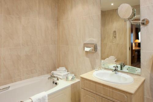 La salle de bains est pourvue d'une baignoire, d'un lavabo et d'un miroir. dans l'établissement Holiday Inn Barnsley, an IHG Hotel, à Barnsley