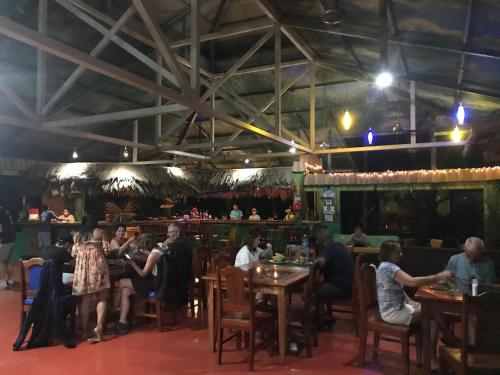 a group of people sitting at tables in a restaurant at La Palapa Hut Nature Hostel in Puerto Jiménez