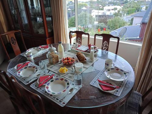 a table with plates of food on it with a window at Moana View in Picton