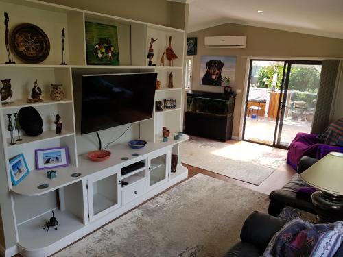 a living room with a flat screen tv on a white entertainment center at Sundowner Cottage in Sanctuary Point