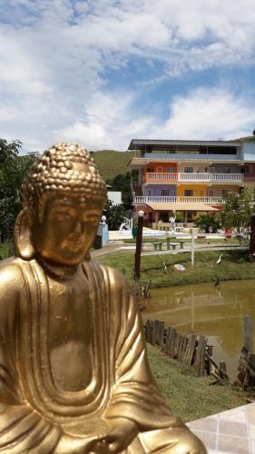 a gold statue of a buddha in front of a building at Pousada 7 Estrelas in Ipiabas