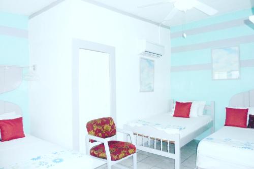 a white room with two beds and a chair at Hotel Ivania´s in Masaya