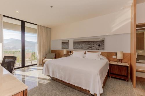 ein Schlafzimmer mit einem weißen Bett und einem großen Fenster in der Unterkunft Hotel Mio Vallarta Unique & Different- Adults Only in Puerto Vallarta