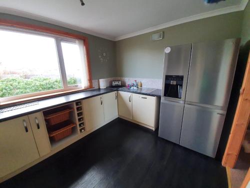 a kitchen with a stainless steel refrigerator and a window at Taigh nam Piobaireach in Balivanich