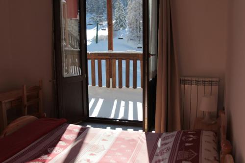 a bedroom with a door open to a snow covered yard at Hotel Al Foiron in Claviere