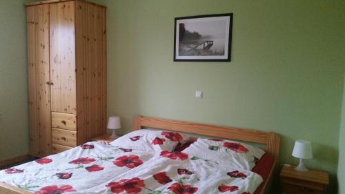 ein Schlafzimmer mit einem Bett mit roten Blumen darauf in der Unterkunft Ferienhof Stobbe in Grube