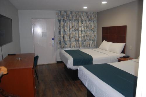a hotel room with two beds and a desk and a television at Motel 6-Tupelo, MS - Downtown in Tupelo