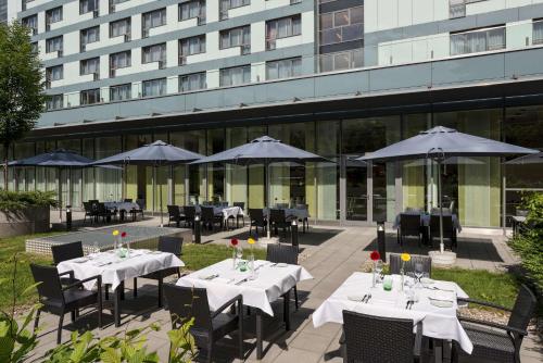 
a patio area with tables, chairs and umbrellas at Park Inn by Radisson Linz in Linz
