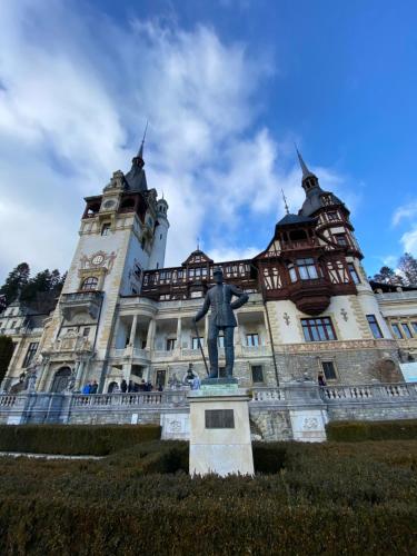 a statue in front of a building with a clock tower at Vila De Argint in Sinaia