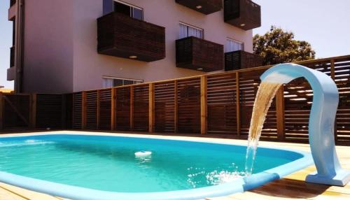 uma piscina com uma fonte de água em frente a um edifício em Pousada Suítes do Rosa em Praia do Rosa
