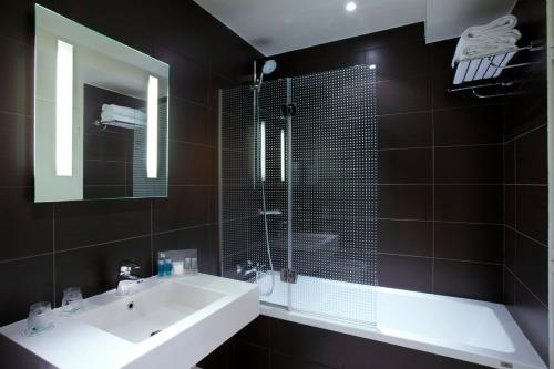 a bathroom with a sink and a shower and a mirror at Holiday Inn Paris Opéra - Grands Boulevards by IHG in Paris