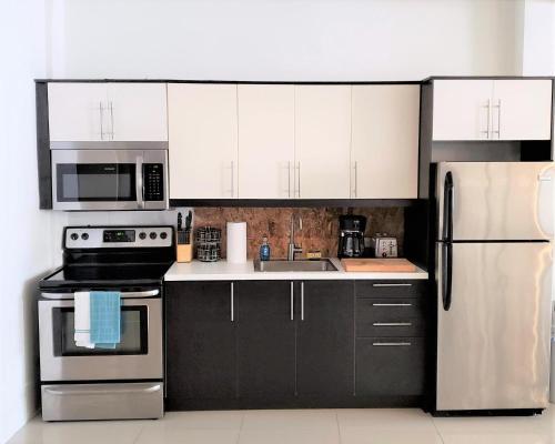 a kitchen with black cabinets and white appliances at KASA The Lofts 201 HUGE 2 bed 2 bath for 6 Washer Dryer in San Juan