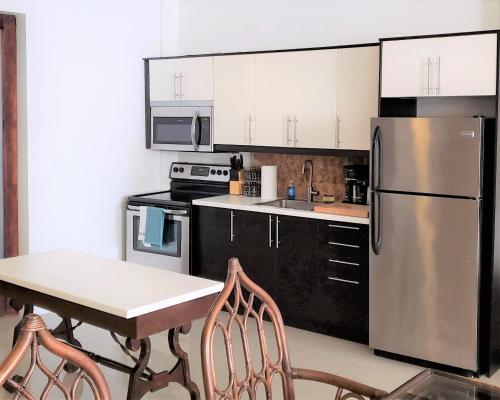 a kitchen with a table and a stainless steel refrigerator at KASA The Lofts of Old San Juan 201 HUGE 2 bed 2 bath for 6 Washer Dryer in San Juan