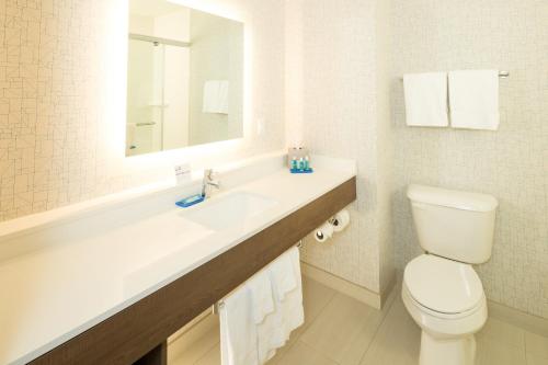 a bathroom with a toilet and a sink with a mirror at Holiday Inn Express & Suites - Gaylord by IHG in Gaylord