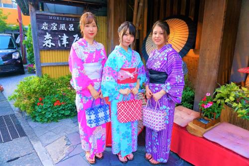 three women are standing in front of a building at Morizuya in Toyooka