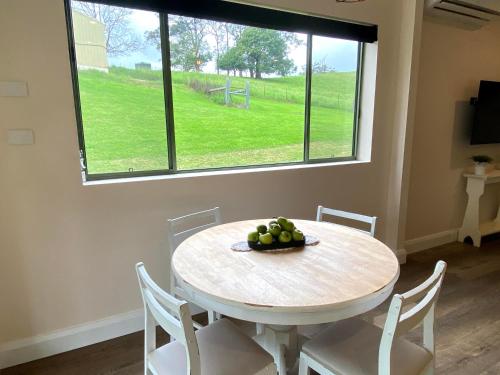 a white table with chairs and a bowl of fruit on it at Waterfall Unit Farm Stay in Upper Orara