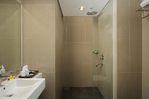 a bathroom with a shower and a sink and a sink at KHAS Tugu Hotel Yogyakarta in Yogyakarta
